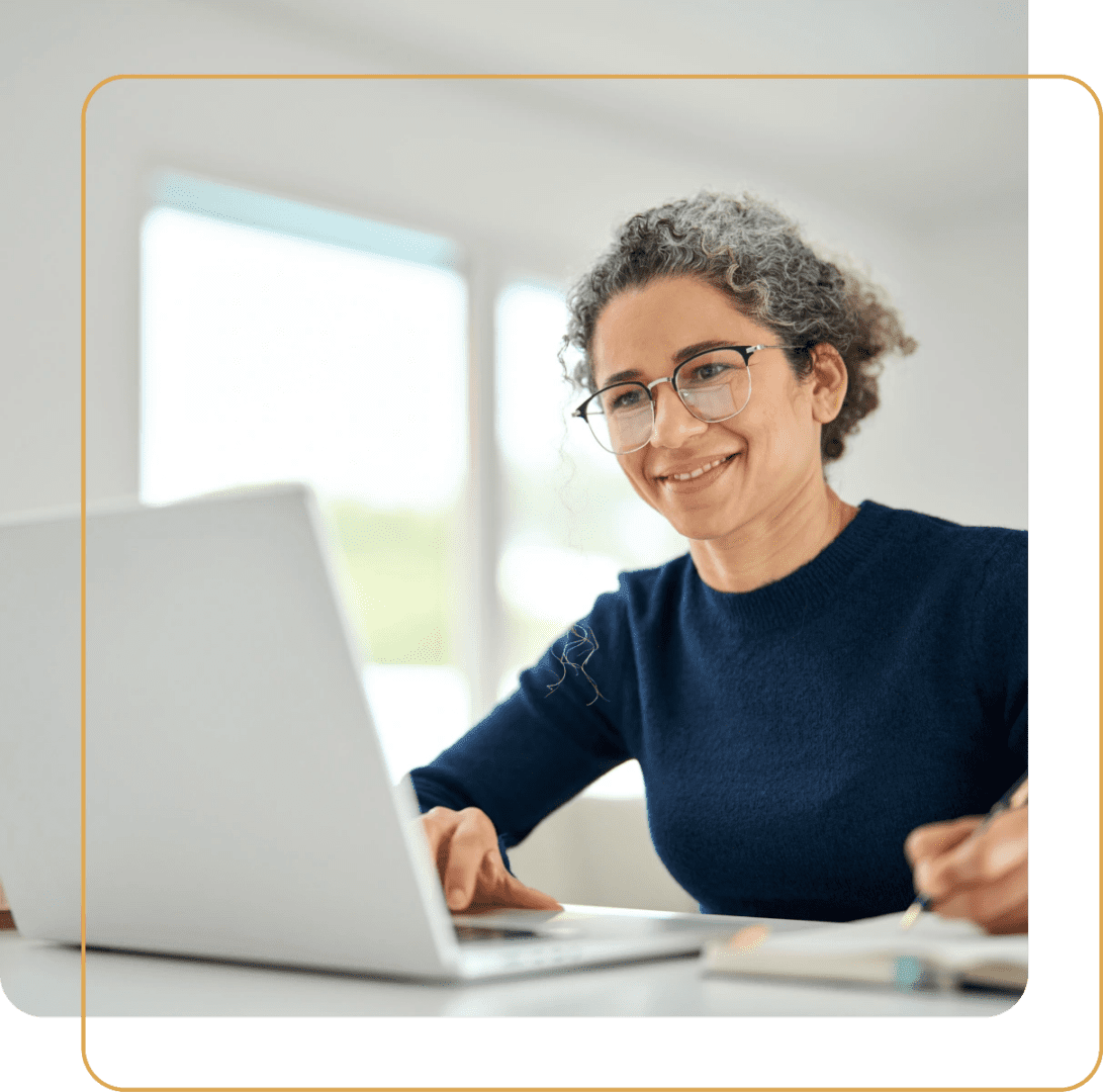 A woman working on a laptop with a thoughtful expression.