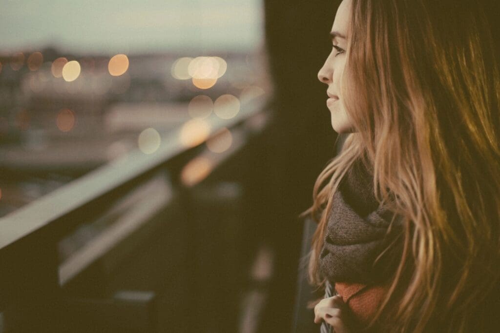 Woman gazing from balcony at sunset.